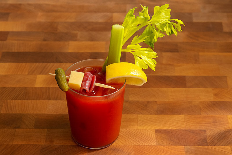 Bloody Mary cocktail with garnishes on a wooden surface