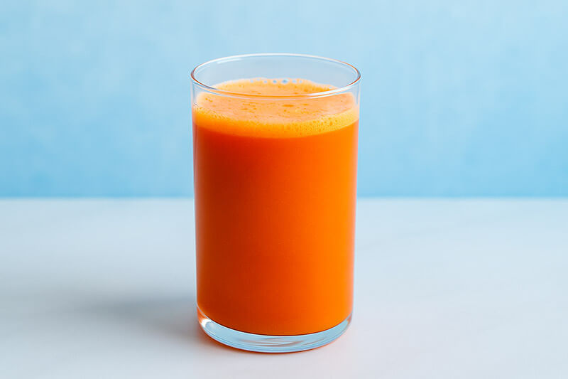 Glass of fresh squeezed juice on a light blue background
